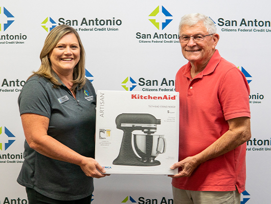Picture of the Dade City Branch Manager along with the winner of SACFCU's Mobile Banking Contest. Both of them are holding up the price of a Kitchenaid Stand Mixer