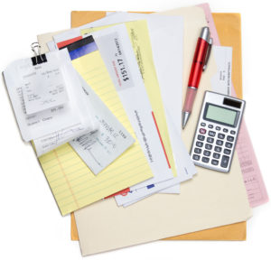 A pile of bills and receipts being calcualted over a few folders on a white background