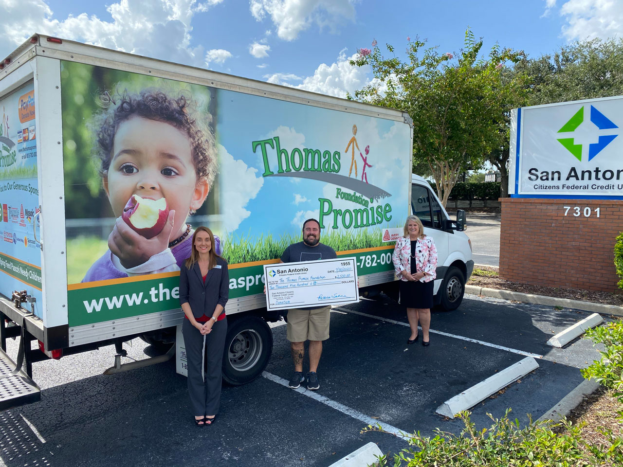 Two SACFCU Employees presenting a big check to a Thomas Promise Foundation Employee